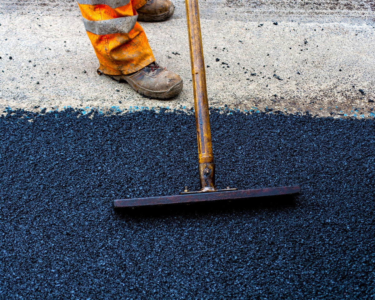 Worker raking asphalt