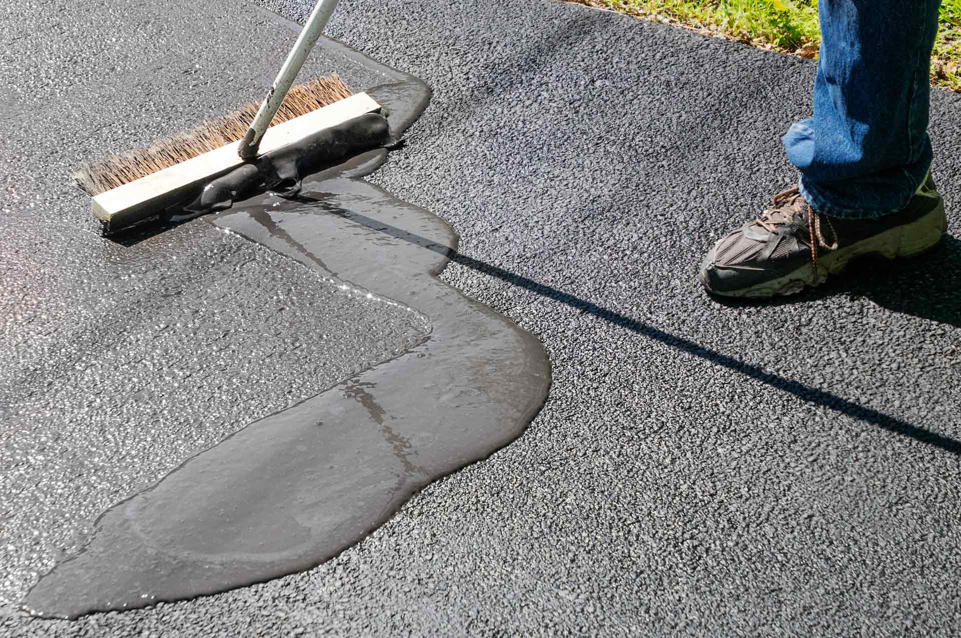 Spreading asphalt resealer onto driveway for maintenance